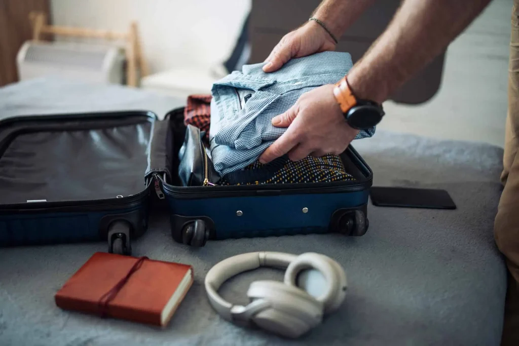 Homem arrumando a mala de mão com roupas e acessórios para a viagem.